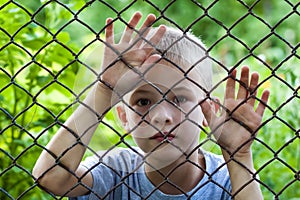 Portrait of a little boy behind chain link fence