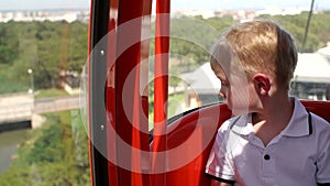 Portrait of a little boy in a cable car cabin that rises up a high mountain.