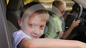 Portrait of a little boy in a car in the front seat, he gives a thumbs up.