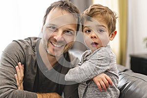 Portrait of little boy with father having fun on sofa with attitude