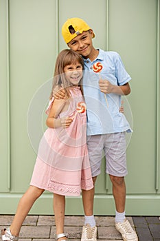 Portrait of little boy and girl with candies on green background