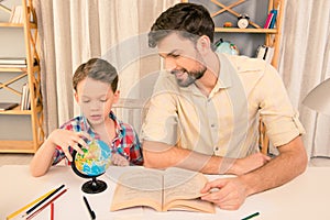 Portrait of little boy and his father learning geography at home