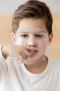 Portrait of little boy hold finger with moustache drawing