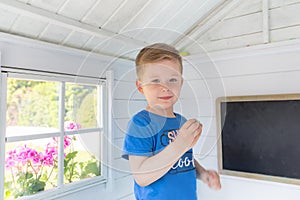 Portrait of little boy inside his garden house with chalkboard