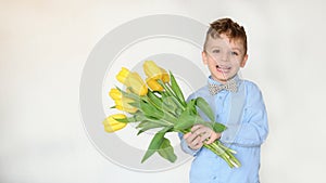 Portrait of a little boy kid holding a bouquet of yellow tulips and smile