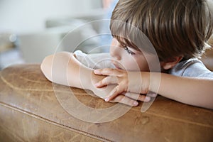 Portrait of little boy leaning on sofa looking away