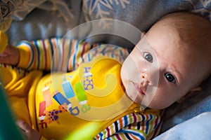 A portrait of a little boy lying in a crib looking at us