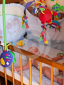 A portrait of a little boy lying in a crib playing