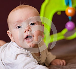 A portrait of a little boy lying in a crib playing