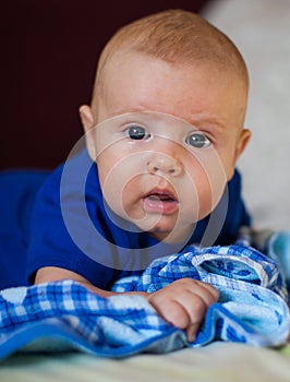 A portrait of a little boy lying in a crib playing