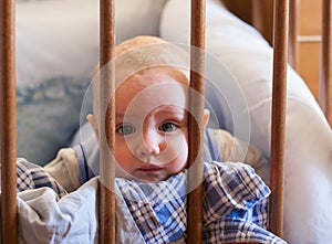 A portrait of a little boy lying in a crib playing