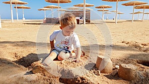 Portrait of cute little boy making sand castle on the sea beach