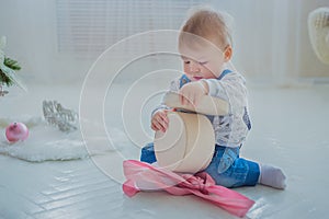 Portrait of little boy playing with empty gift box in bright white room