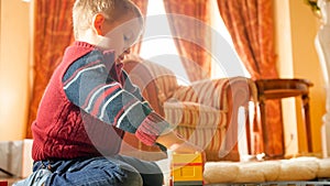 Portrait of little boy playing with toys on wooden floor at living room against big window