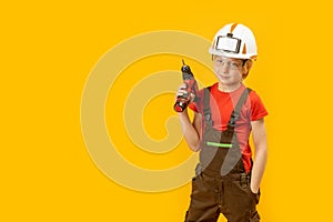 Portrait of little boy pretends to drill wall with drill, yellow isolated background. Boy teenager as builder worker. Copy space,