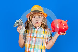 Portrait of a little boy putting money on a moneybox. Child saving money in a piggybank on blue background. Business