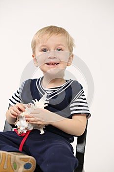 Portrait of a little boy with a seashell in his hands, light background