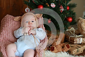 Portrait of a little boy sitting near Christmas tree