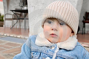 Portrait of a little boy in warm clothes, a denim jacket and a knitted hat