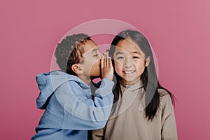 Portrait of little boy whispering something to his friend.