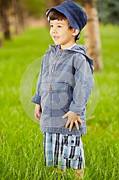 Portrait of little boy who stands on grassy lawn