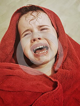 Portrait of Little Brazilian girl crying with a red towel on her head