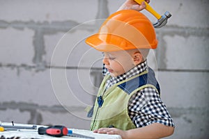 Portrait of little builder in hardhats with instruments for renovation on construction. Builder boy, carpenter kid with