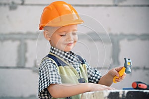 Portrait of little builder in hardhats with instruments for renovation on construction. Builder boy, carpenter kid with