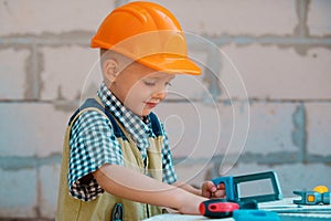 Portrait of little builder in hardhats with instruments for renovation on construction. Builder boy, carpenter kid with