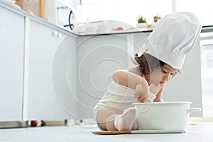 Portrait of little Caucasian adorable kid girl wear chef hat holding wooden spoon or whisk to stir food in pot at home  kitchen