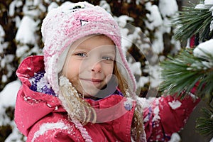 Portrait of little Caucasian blond girl on fir-tree background