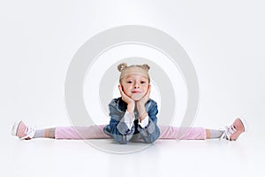 Portrait of little Caucasian cute girl in stylish outfit sitting in a twine on floor isolated over white studio