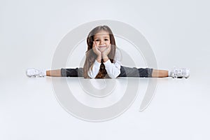 Portrait of little Caucasian cute girl wearing hoodie with jeans sitting on a twine and having fun  over white