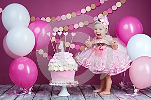 Portrait of a little cheerful birthday girl with the first cake. Eating the first cake. Smash cake