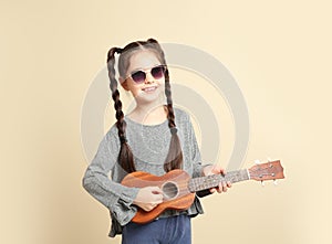 Portrait of little cheerful girl playing guitar