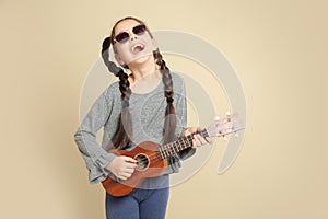 Portrait of little cheerful girl playing guitar