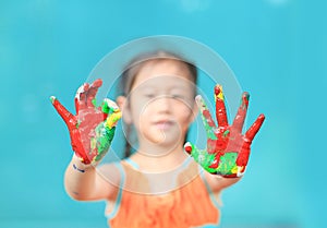Portrait of little cheerful girl showing her colorful hands painted with ok sign. Focus at baby hands