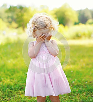 Portrait of little child closes her face outdoors