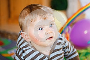 Portrait of little child, cute adorable baby boy playing with colorful toys. Happy, curious kid at home, indoors.