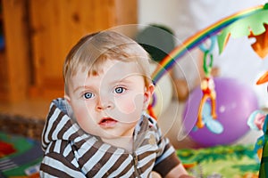 Portrait of little child, cute adorable baby boy playing with colorful toys. Happy, curious kid at home, indoors.