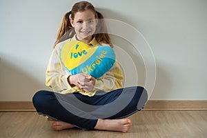 Portrait of little child girl hug pillow with ukrainian flag colours