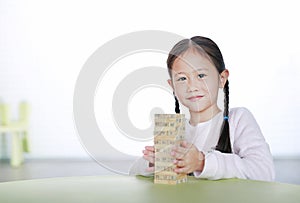 Portrait of little child girl playing wood blocks tower game for Brain and Physical development skill in a classroom. Focus at