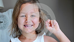 Portrait of little child girl is showing her lost milk tooth and smiling