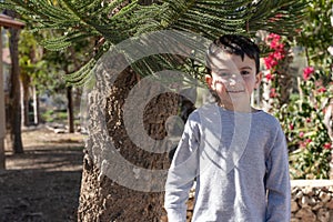 Portrait of little child standing near tree at sunny day.