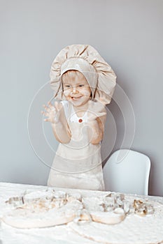 Portrait of a little cook kneading dough in an apron and a chef& x27;s hat.