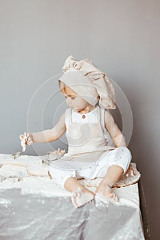 Portrait of a little cook kneading dough in an apron and a chef& x27;s hat.