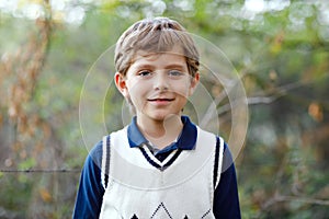 Portrait of little cool kid boy in forest. Happy healthy child having fun on warm sunny day early autumn. Family, nature