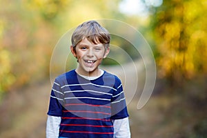 Portrait of little cool kid boy in forest. Happy healthy child having fun on warm sunny day early autumn. Family, nature