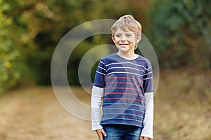 Portrait of little cool kid boy in forest. Happy healthy child having fun on warm sunny day early autumn. Family, nature