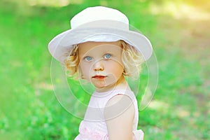 Portrait of little curly girl child wearing a white hat